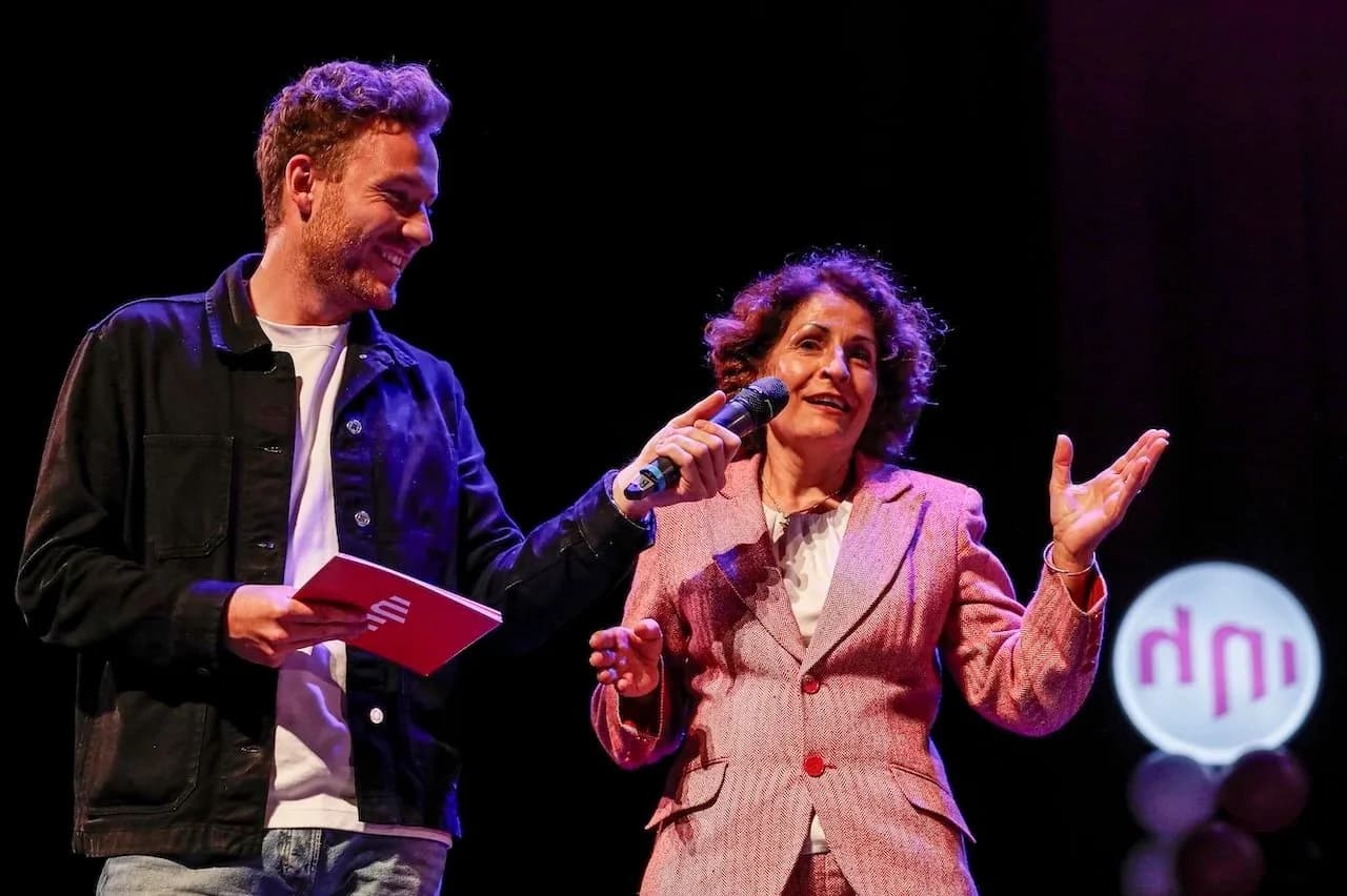 Rudy Nicola als dagvoorzitter op het podium, in gesprek met een gast